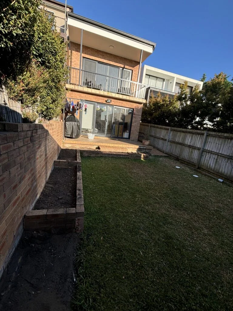 Dover Heights backyard before the deck build, old brick paved patio and lawn