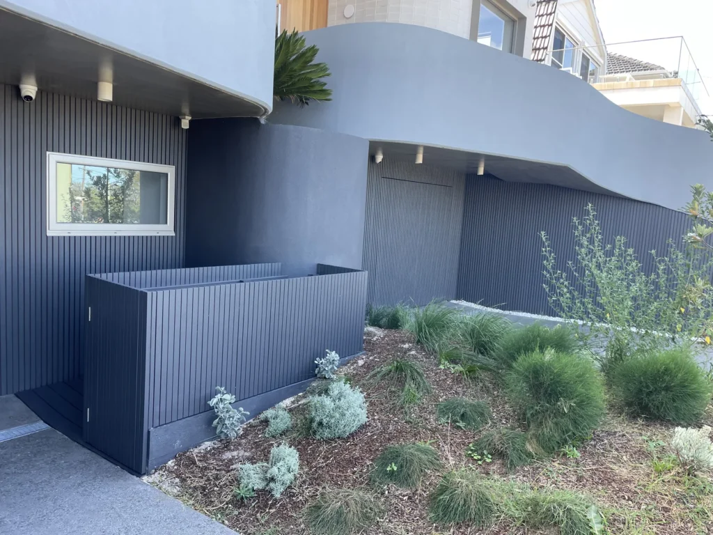 Bin and scooter store in Maroubra with the gate shut, platform sitting flush with the sloping curved driveway