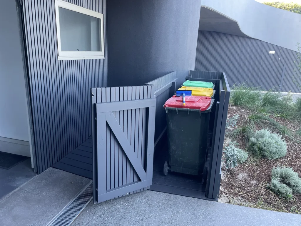 Gate open on the Maroubra bin store showing three wheelie bins inside