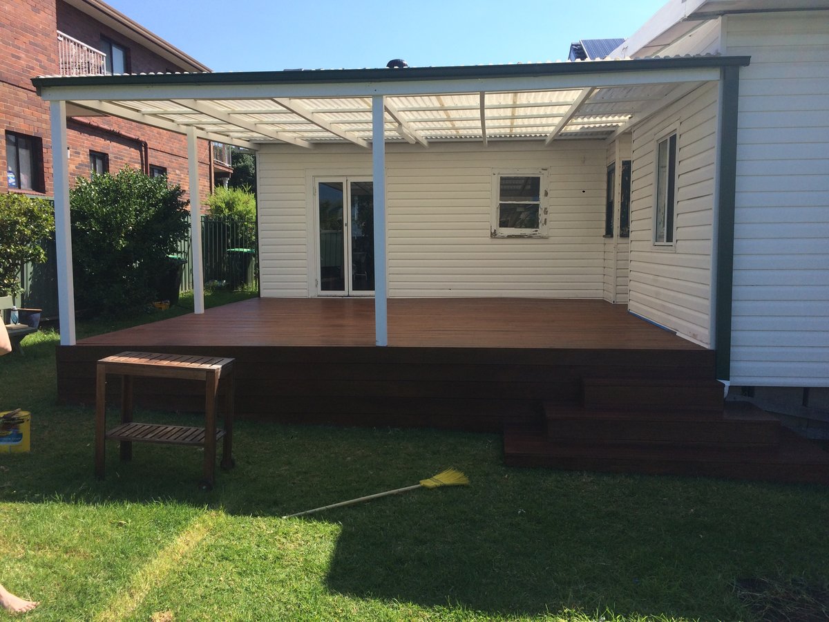 White timber pergola with corrugated polycarbonate roof over a dark-stained deck on a weatherboard house